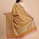 Premium mustard Semi Kataan Silk Banarasi dupatta with golden zari floral jaal work, an ornate oval-motif border and pink tassels.